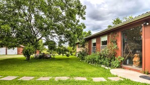 A well-maintained lawn with stone stepping stones leading to a building with large windows and a brick exterior. - On Scenic 60-acre Farm: Carmine Cottage w/ Porch (Carmine)