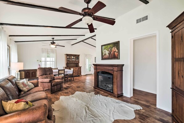 A spacious living room with a fireplace, leather sofas, and a ceiling fan. - On Scenic 60-acre Farm: Carmine Cottage w/ Porch (Carmine)