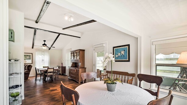 A dining area with a round table, chairs, and a potted plant. There is a wooden cabinet and a framed picture on the wall. - On Scenic 60-acre Farm: Carmine Cottage w/ Porch (Carmine)