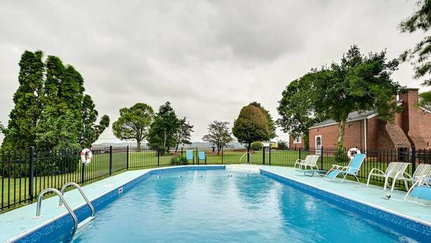 A rectangular swimming pool with a blue tiled edge, surrounded by a black metal fence.