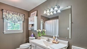 A bathroom with a vanity, toilet, and a window with a decorative valance.