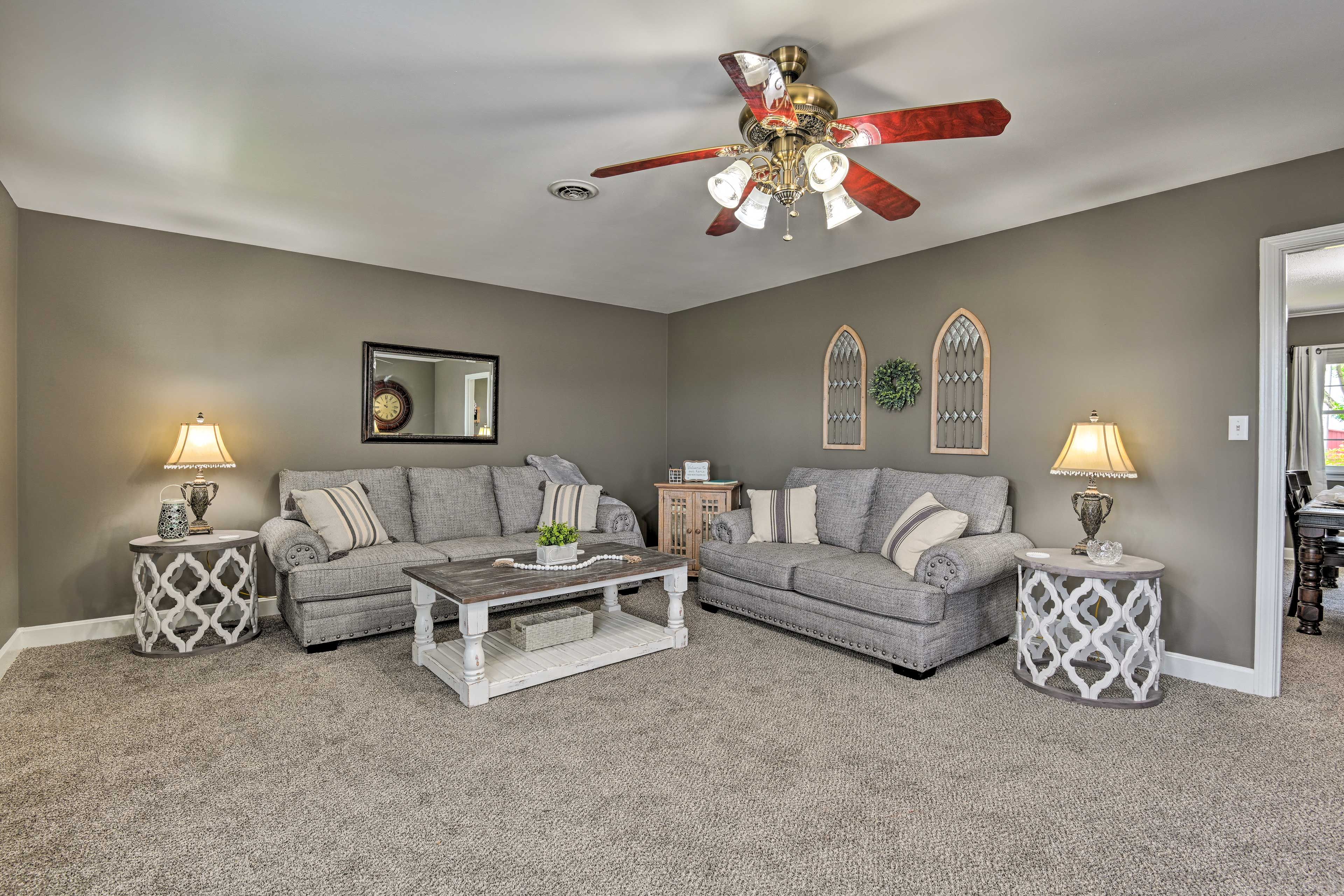 A living room with two grey sofas, a wooden coffee table, and two decorative side tables with lamps.