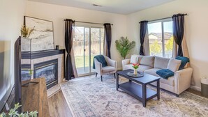 A living room with a fireplace, a sofa, a coffee table, and a large window with curtains.