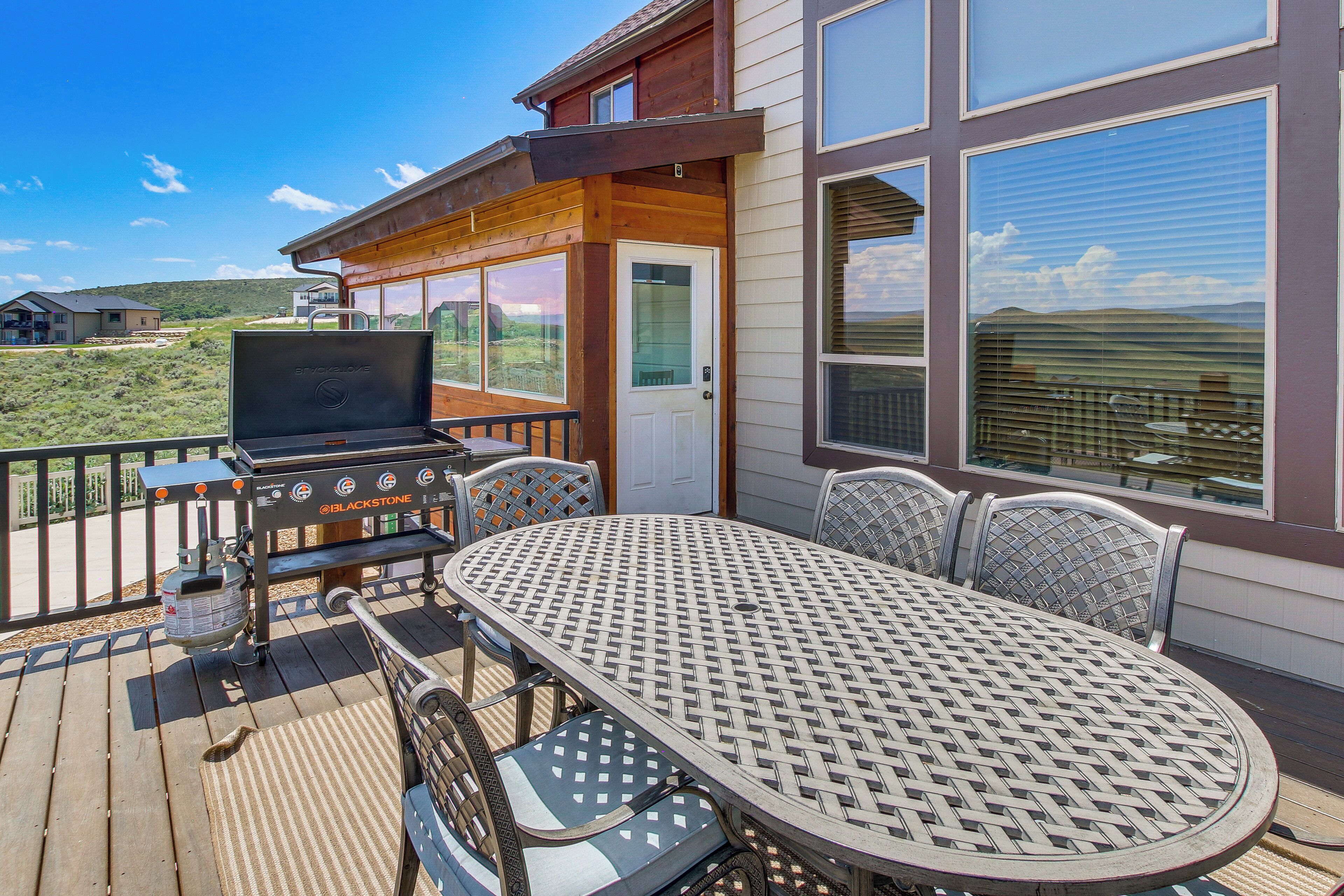An outdoor deck with a grill, a table, and chairs.