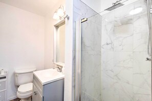 Ein Badezimmer mit Toilette, Waschbecken, Spiegel und einer Duschkabine.