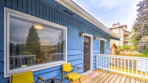 Ein blaues Haus mit einer Holzterrasse, zwei gelben Stühlen und einem kleinen Tisch.