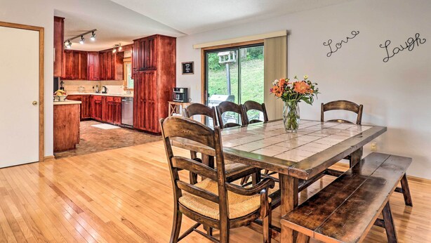 Ein Essbereich mit Holztisch und Stühlen, einer Bank und einer Vase mit Blumen.