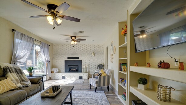 A living room with a fireplace, a sofa, a coffee table, and a television on a shelf. - Chic Silver City Getaway w/ Patio + Gas Grill (Silver City)