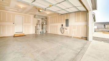 A spacious garage with a concrete floor, a white door, and a visible water heater.
