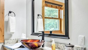Ein Badezimmer mit einem Holzbadschränken, einem großen Spiegel und einem Fenster über dem Waschbecken.