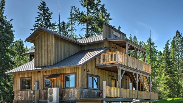 Eine Holzhütte mit Balkon und überdachter Veranda, umgeben von Bäumen.