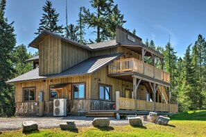 A wooden cabin with a balcony and a covered porch, surrounded by trees. - Columbia Falls Apt ~ 17 Mi to Whitefish Resort! (Columbia Falls)
