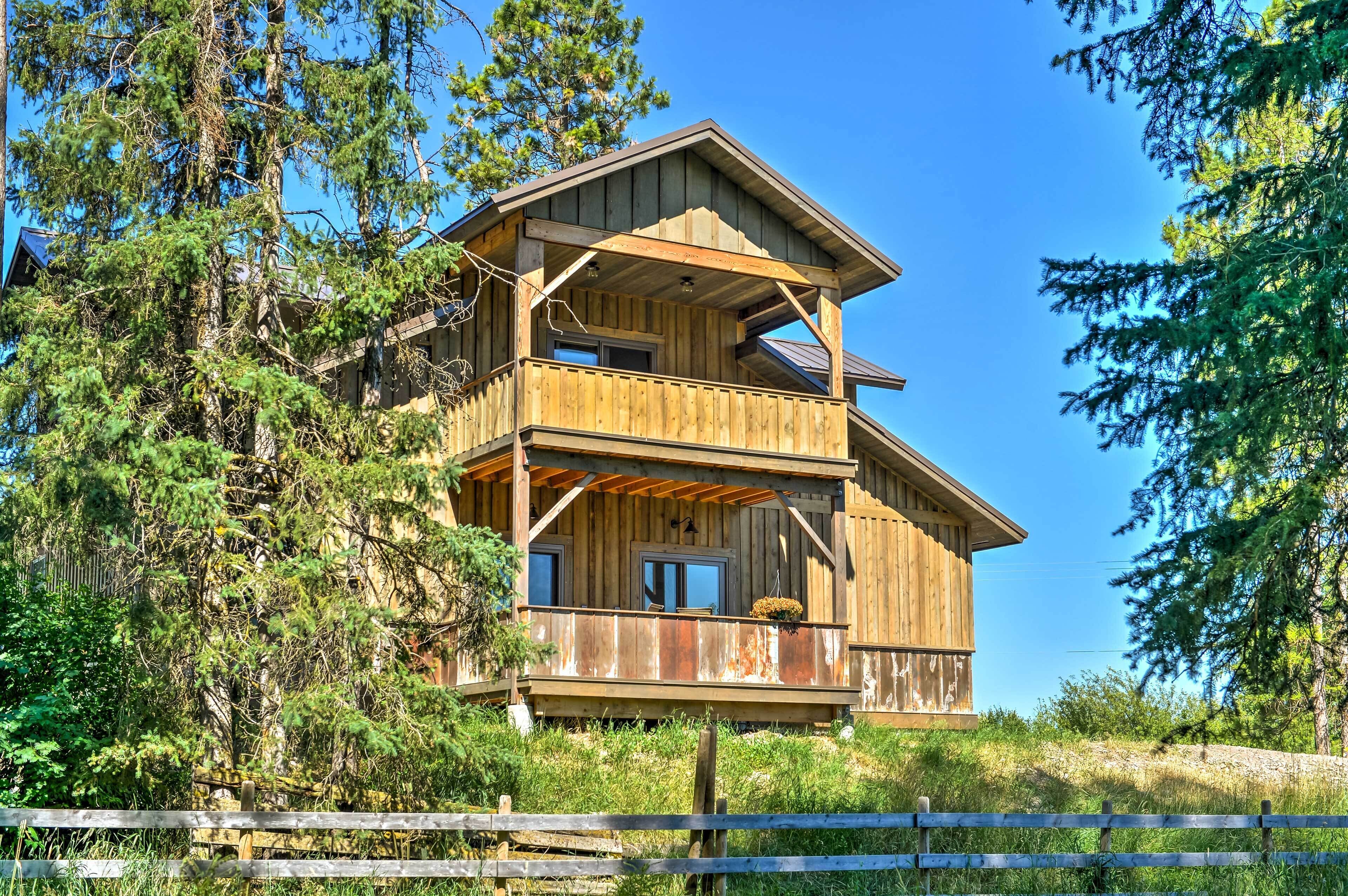 A wooden cabin with a balcony, surrounded by trees.