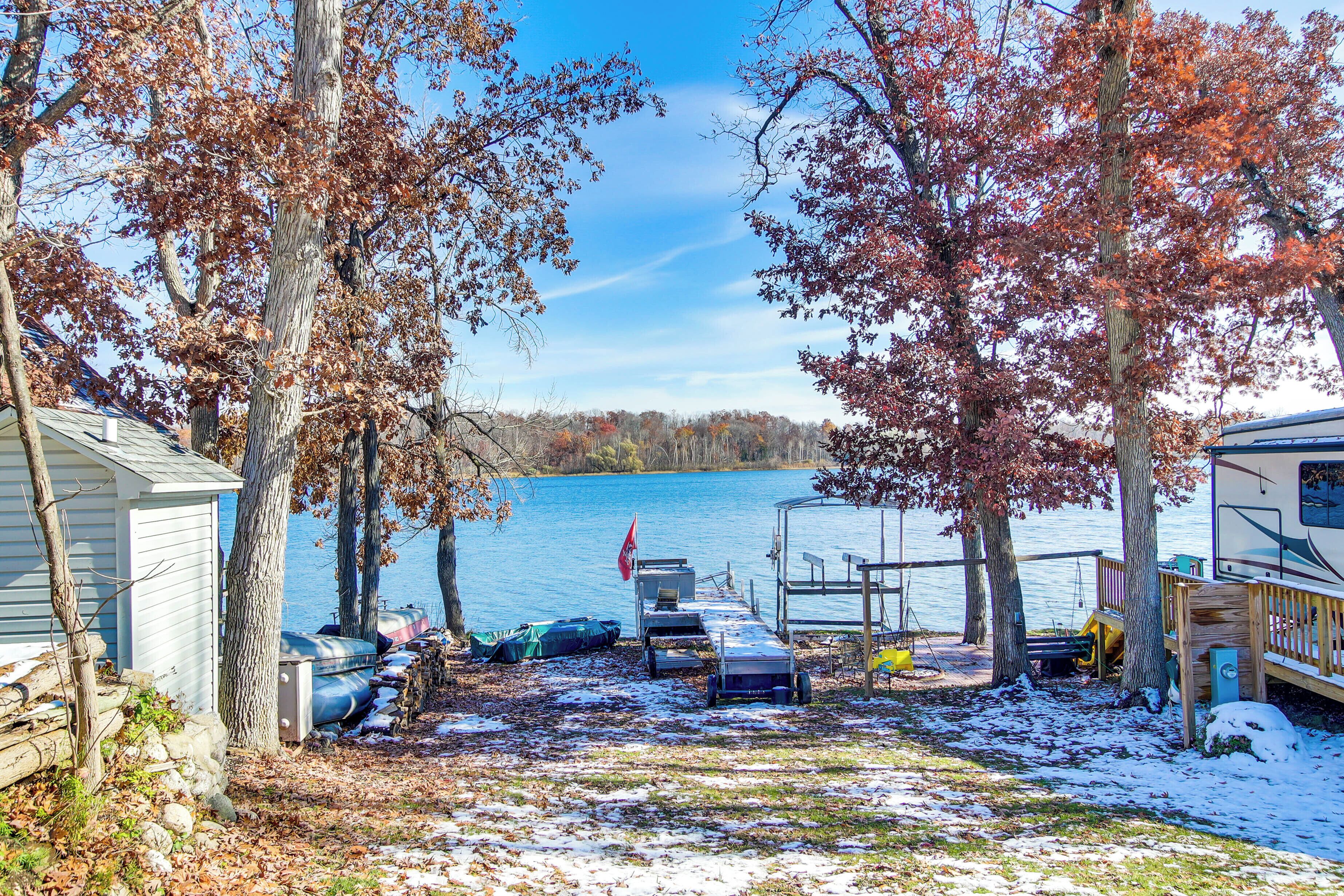 A lakeside cabin with a dock, a covered area, and a boat.