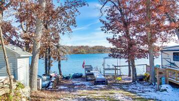 A lakeside cabin with a dock, a covered area, and a boat.