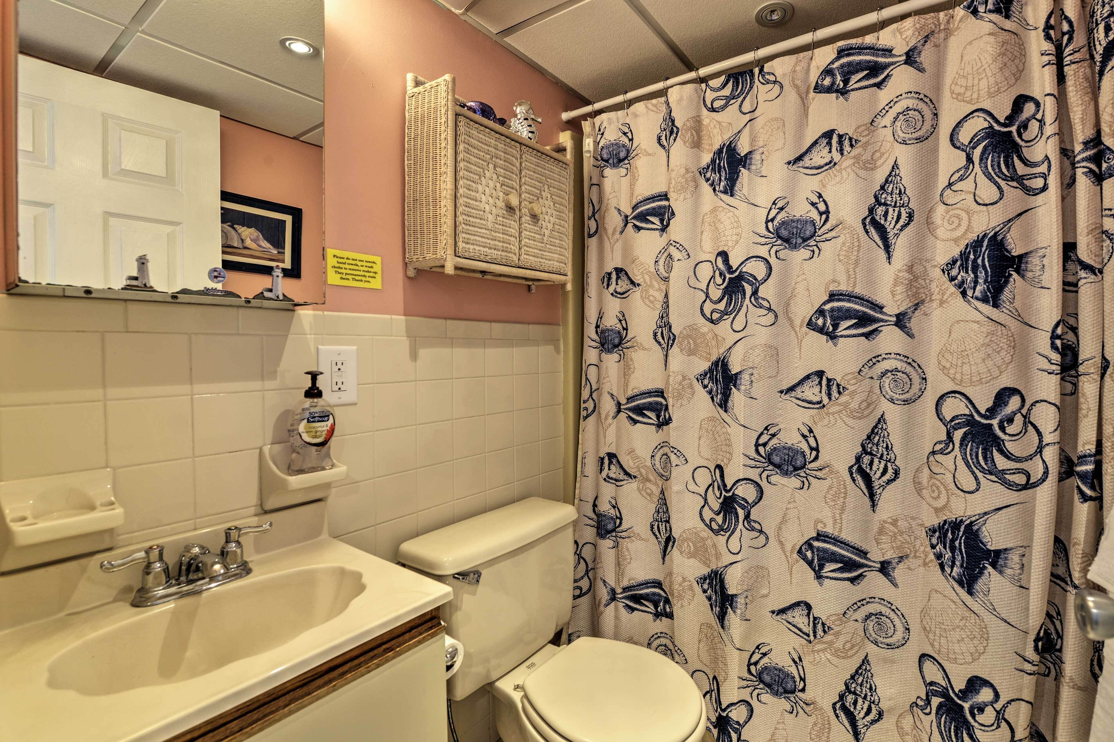 Un bagno con lavandino, water e tenda doccia a fantasia pesce.