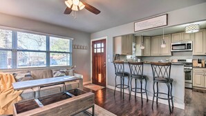 A modern kitchen with bar stools, a wooden dining table, and a ceiling fan. - Cozy Duplex, Walk to Bentonville City Square! (Bentonville)