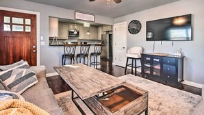 A modern living room with a wooden coffee table, a sofa, and a dining area with bar stools. - Cozy Duplex, Walk to Bentonville City Square! (Bentonville)