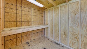 A room under construction with exposed wooden walls and ceiling, fluorescent lighting, and a wooden shelf. - Cozy Duplex, Walk to Bentonville City Square! (Bentonville)
