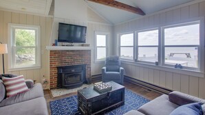 Una sala de estar acogedora con chimenea, televisor y vista al agua.