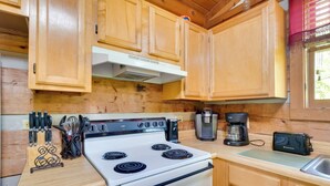 A kitchen with wooden cabinets, a white stove, and various kitchen appliances. - Covered Deck & Hot Tub: Cozy Gatlinburg Cabin (Gatlinburg)