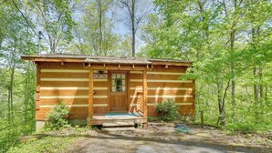 A rustic wooden cabin with a porch, surrounded by trees. - Covered Deck & Hot Tub: Cozy Gatlinburg Cabin (Gatlinburg)
