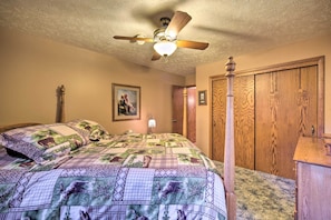 A bedroom with a bed covered in a patterned quilt, a ceiling fan, wooden wardrobe, and a framed picture on the wall. - Cozy Hayward Cottage w/ Dock & Lakefront View (Hayward)