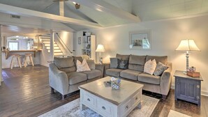 Ein geräumiges Wohnzimmer mit zwei Sofas, einem Couchtisch und einem Beistelltisch. Im Hintergrund ist eine Treppe zu einer oberen Ebene zu sehen.