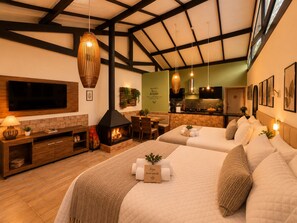 A hotel room with a fireplace, a TV, a dining area, and a kitchenette. - Villa Bergamin (Camanducaia)