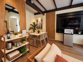 Una sala de estar con sofá, mesa de centro, televisor, microondas y un comedor con mesa y sillas.