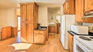 A kitchen with wooden cabinets, a microwave, a stove, and a coffee maker. - Charming Wisconsin Getaway w/ Nearby Lake! (Pound)
