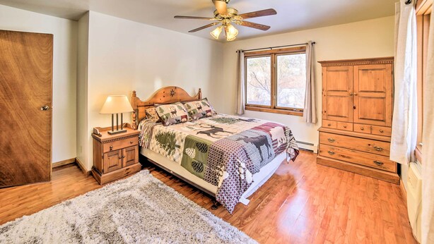 A bedroom with a wooden bed, a ceiling fan, a window, and a wardrobe. - Charming Wisconsin Getaway w/ Nearby Lake! (Pound)