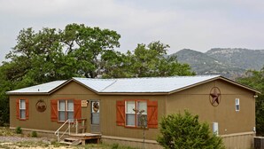 A single-story building with a metal roof, wooden shutters, and a small porch. - Spacious Utopia Family Home w/ Hill Country Views (Utopia)