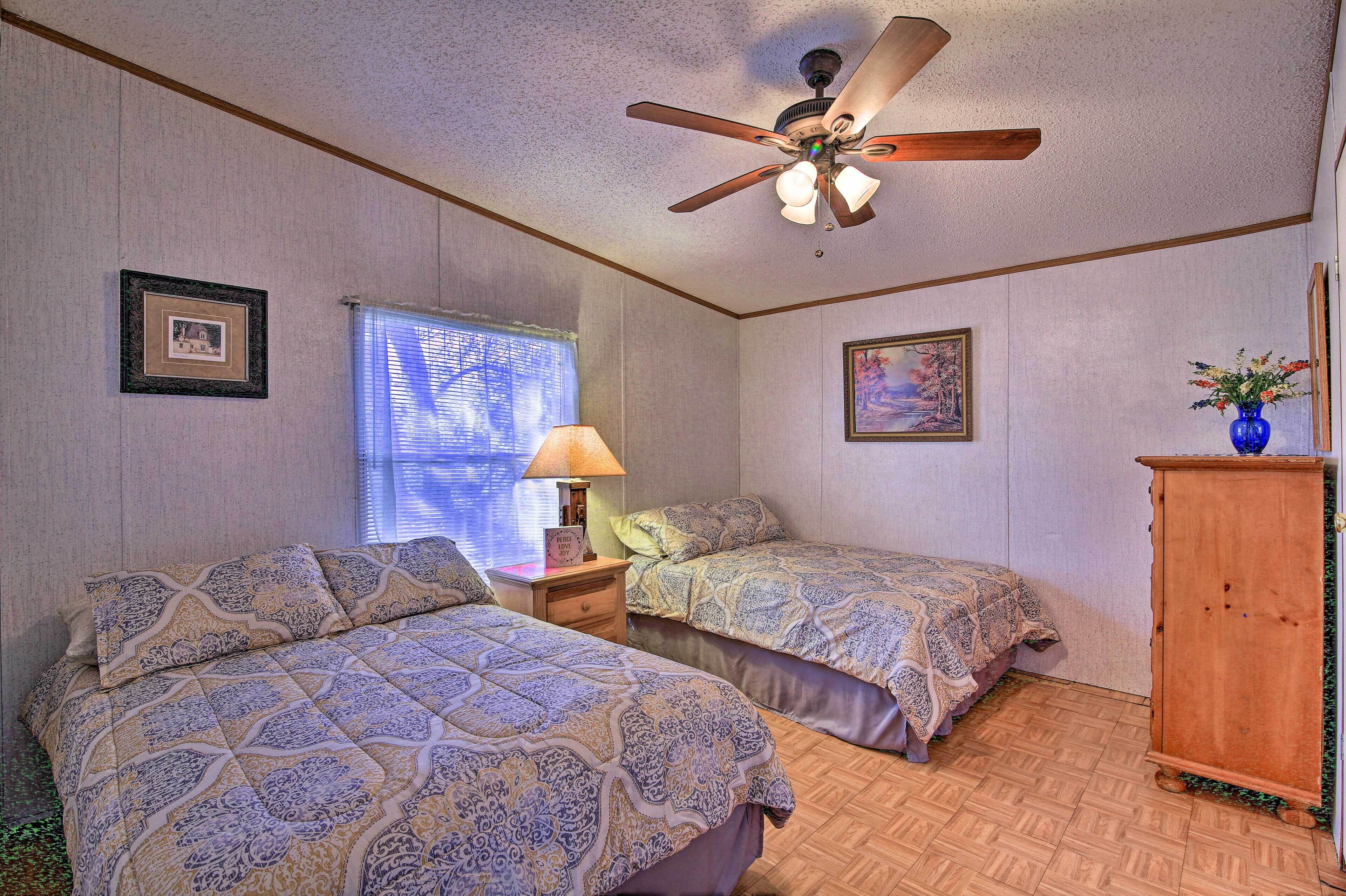 Quarto com duas camas, um ventilador de teto, uma janela com persianas e um armário de madeira.