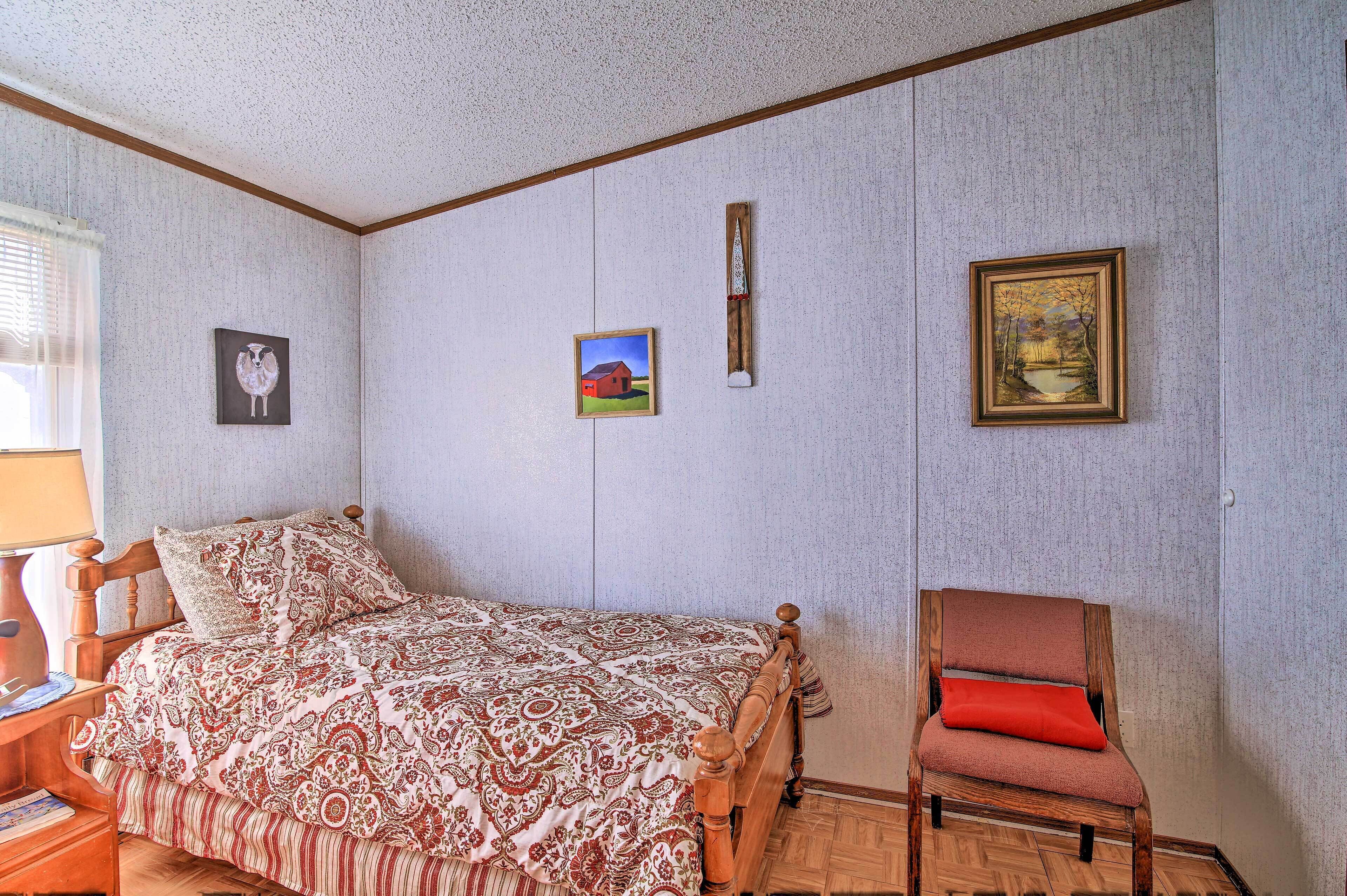 A bedroom with a wooden bed, a chair, and three framed pictures on the wall.
