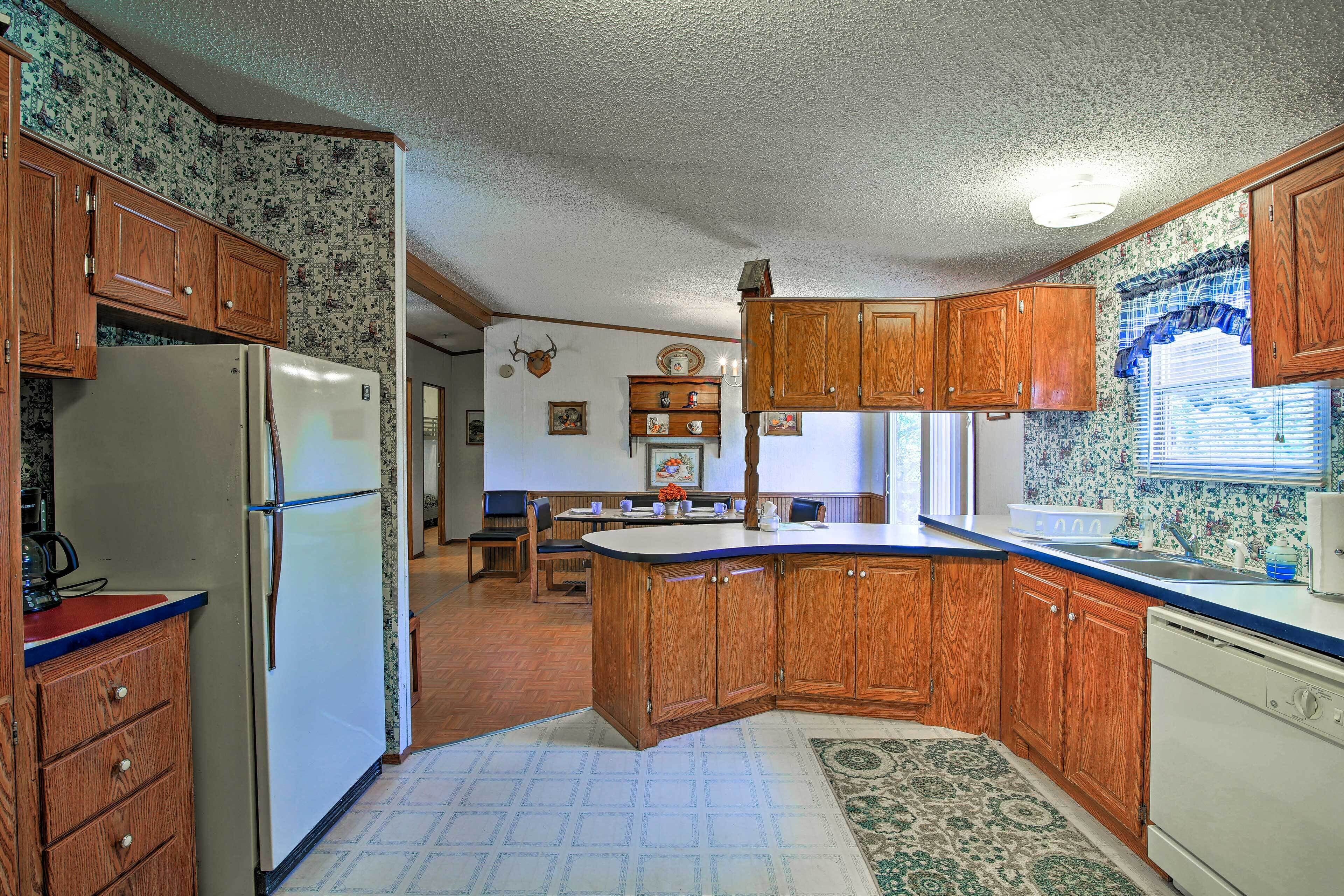 A kitchen with wooden cabinets, a refrigerator, a stove, and a sink.