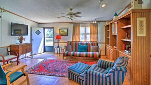 A cozy living room with a sofa, armchairs, a wooden cabinet, and a television. - Spacious Utopia Family Home w/ Hill Country Views (Utopia)