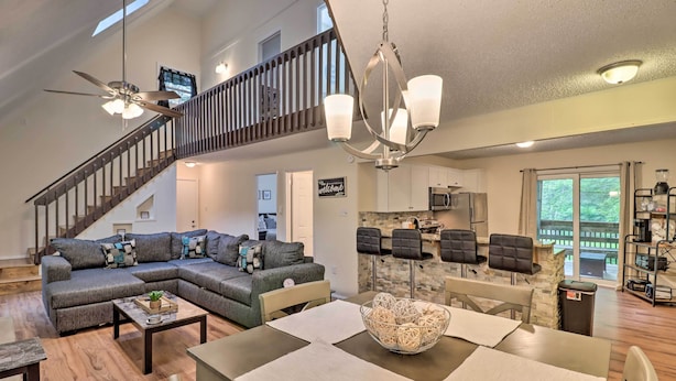 A spacious living room with a sectional sofa, a dining table, and a staircase leading to an upper level. - 7 Mi to Lake Harmony: Home w/ Furnished Deck! (Albrightsville)