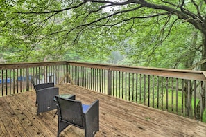 A wooden deck with wicker chairs and a glass table, surrounded by a wooden railing, overlooking a forested area. - 7 Mi to Lake Harmony: Home w/ Furnished Deck! (Albrightsville)