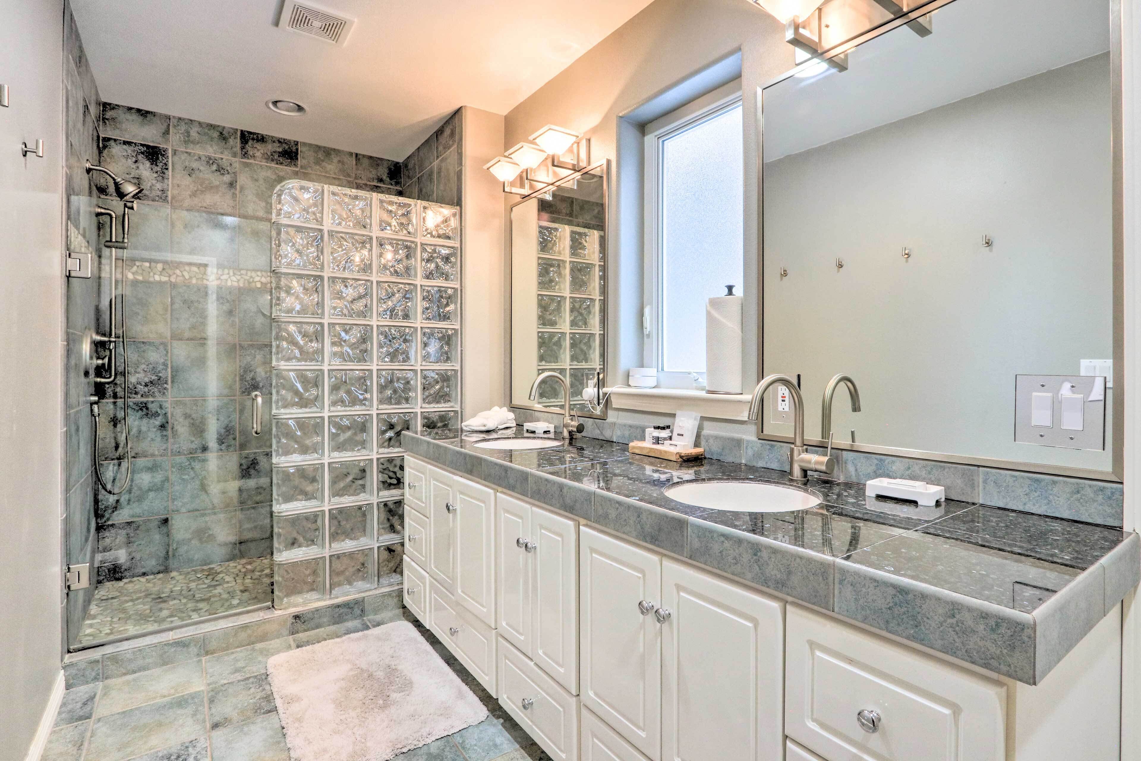 A modern bathroom with a glass shower enclosure, a double sink vanity, and a large mirror.