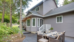 A house with a covered patio area featuring a dining table and chairs, surrounded by trees. - Crystal Bay Home w/ Fireplace Near Ski Resorts (Post Falls)