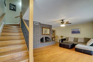 A living room with a fireplace, wooden staircase, and a ceiling fan. - Cozy El Paso Condo w/ Patio ~ 7 Mi to Dtwn! (El Paso)