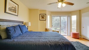 Un dormitorio con una cama grande, un ventilador de techo y vistas al exterior a través de una puerta corrediza de vidrio.