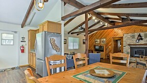 A spacious kitchen with wooden cabinets, a stainless steel refrigerator, and a dining area with a wooden table and chairs. - Cozy Home w/ Patio Near Yosemite National Park! (Mariposa)
