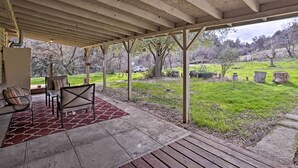 A covered patio with outdoor seating, a view of a grassy yard, and a wooden deck. - Cozy Home w/ Patio Near Yosemite National Park! (Mariposa)