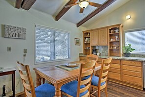 A kitchen with wooden cabinets, a dining table with chairs, and a ceiling fan. - Cozy Home w/ Patio Near Yosemite National Park! (Mariposa)