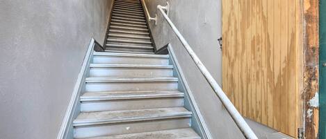 A staircase with a handrail, a wooden door, and a wall with a light fixture.