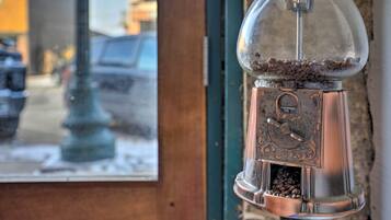 A coffee grinder with a transparent dome, filled with coffee beans, mounted on a wall.