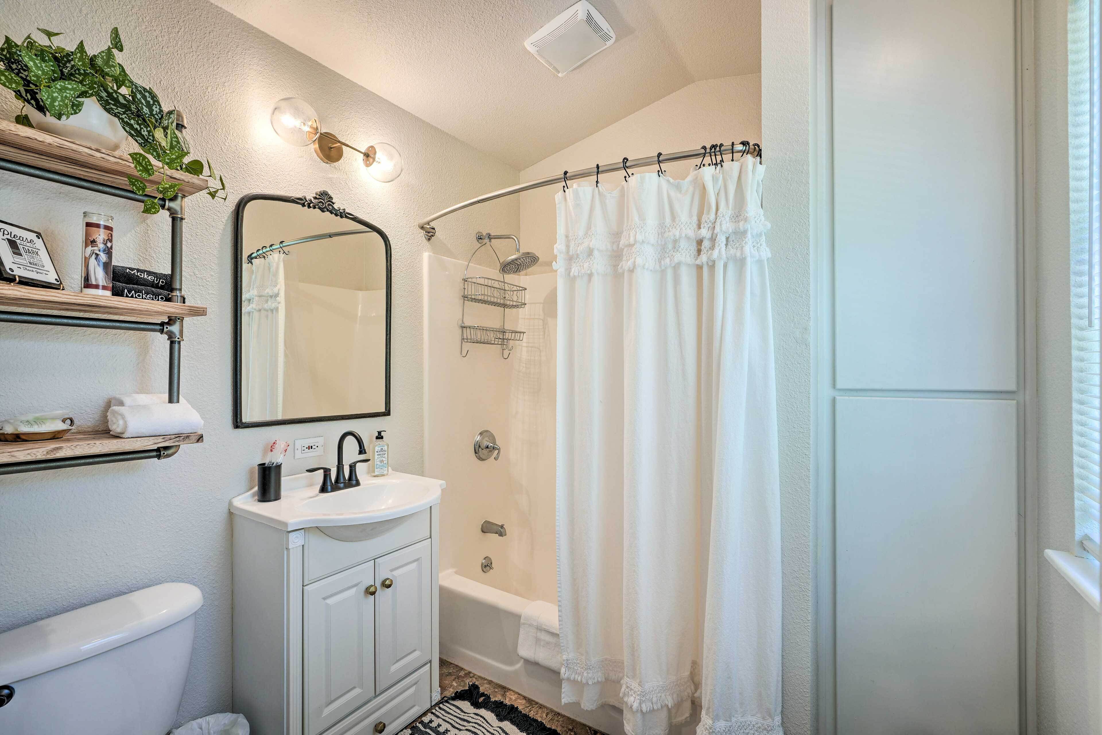 A bathroom with a toilet, sink, vanity, and shower area.
