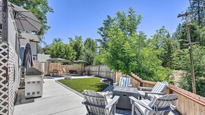 A deck with Adirondack chairs, a grill, and a fire pit.